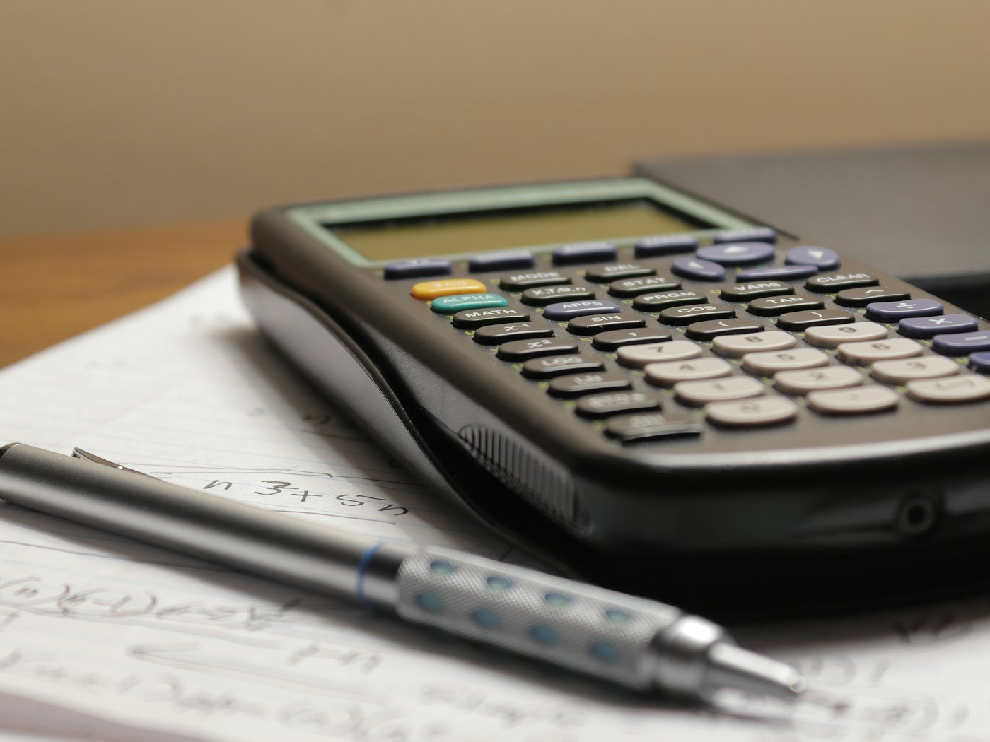 A calculator and pen on a desk of figures
