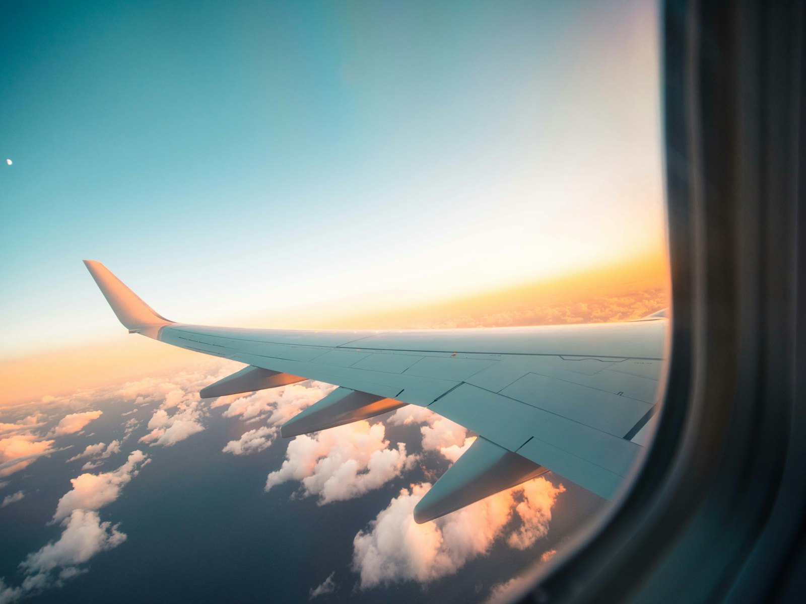 An aircraft wing above the clouds at sunset